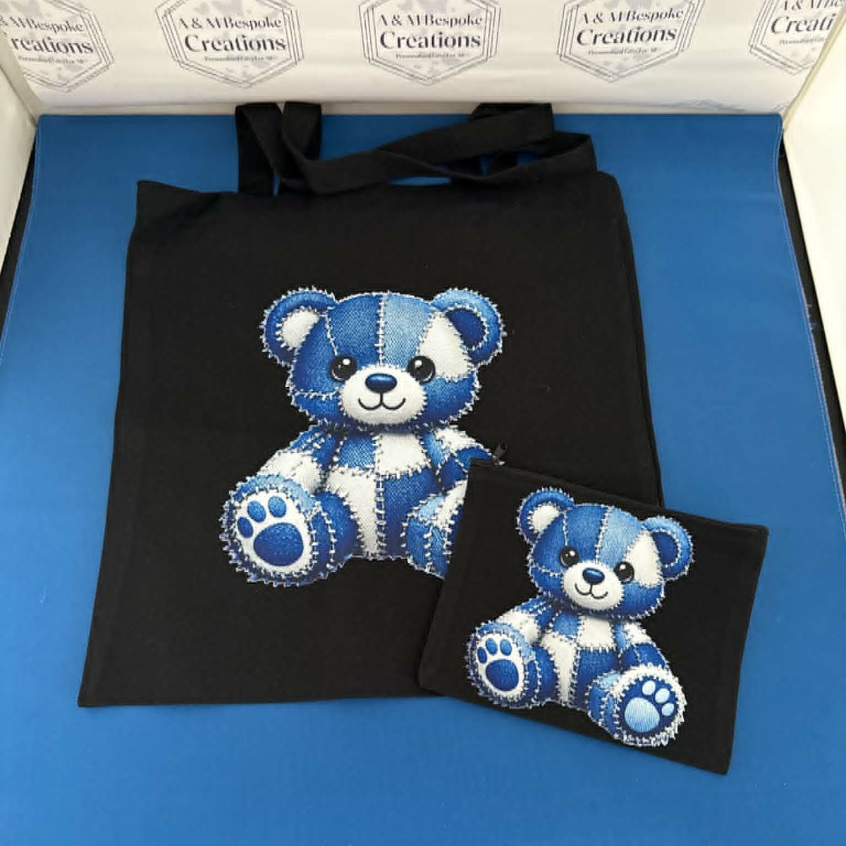 A stylish black tote bag paired with a matching inner pouch, both featuring a beautifully embroidered patchwork denim‑style teddy bear. Cute, practical, and perfect for everyday use or gifting.